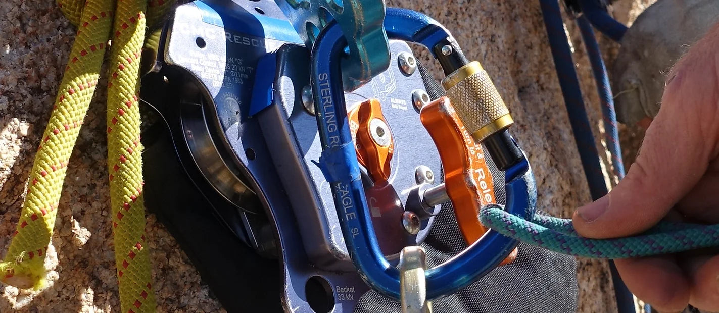 Hand clipping some rope into carabiner.